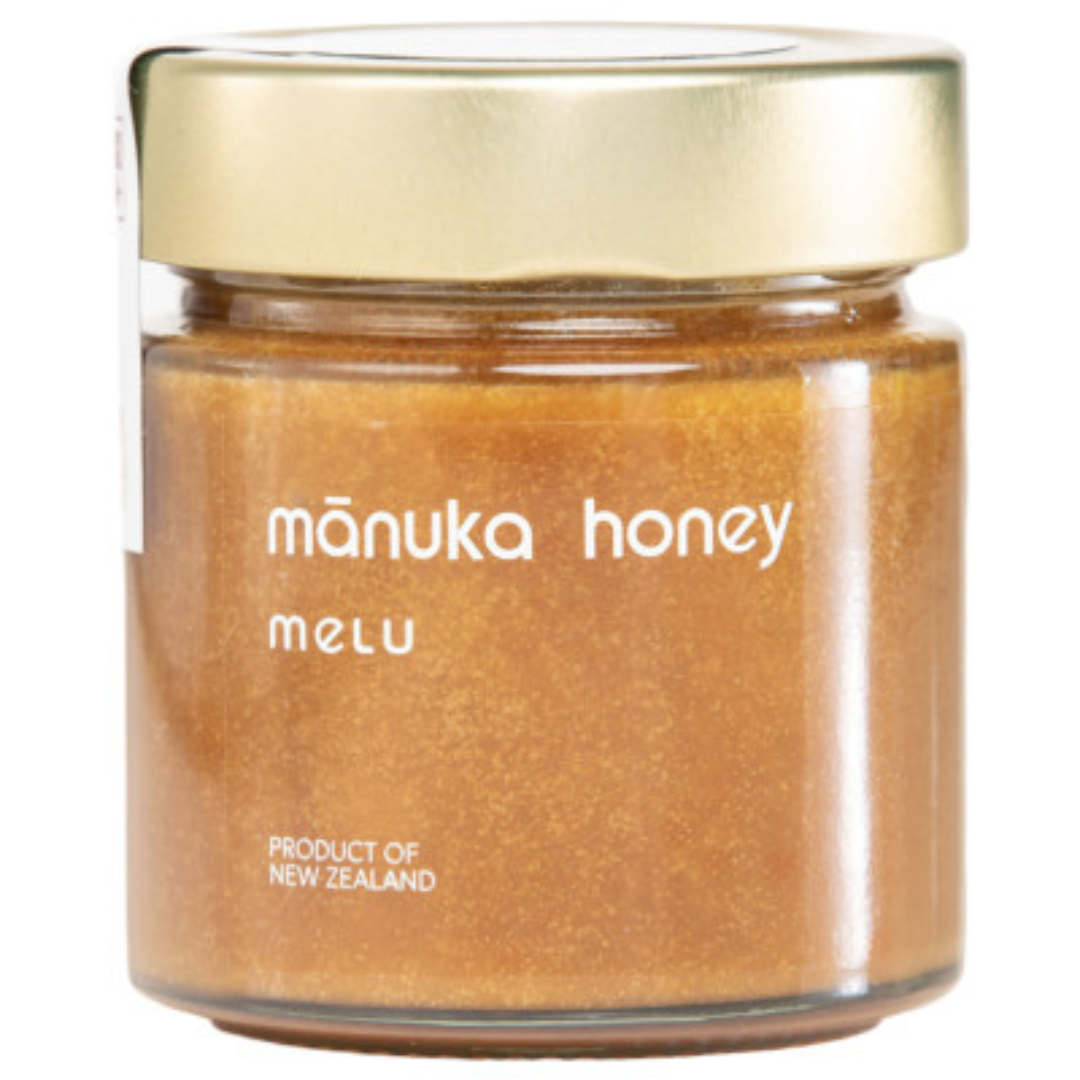 Jar of manuka honey with a gold lid on a white background